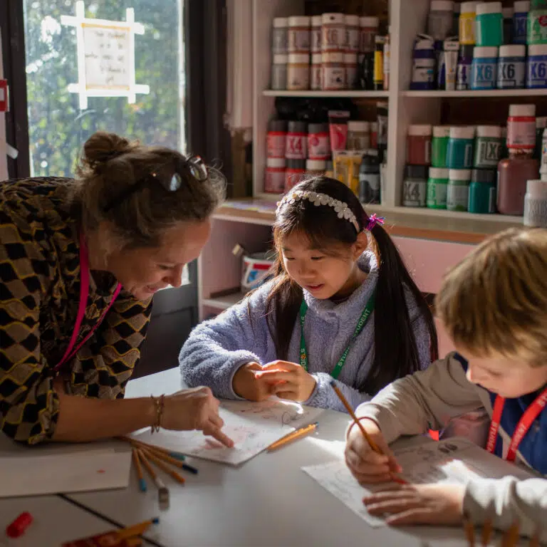 two children and a teacher sat at a desk