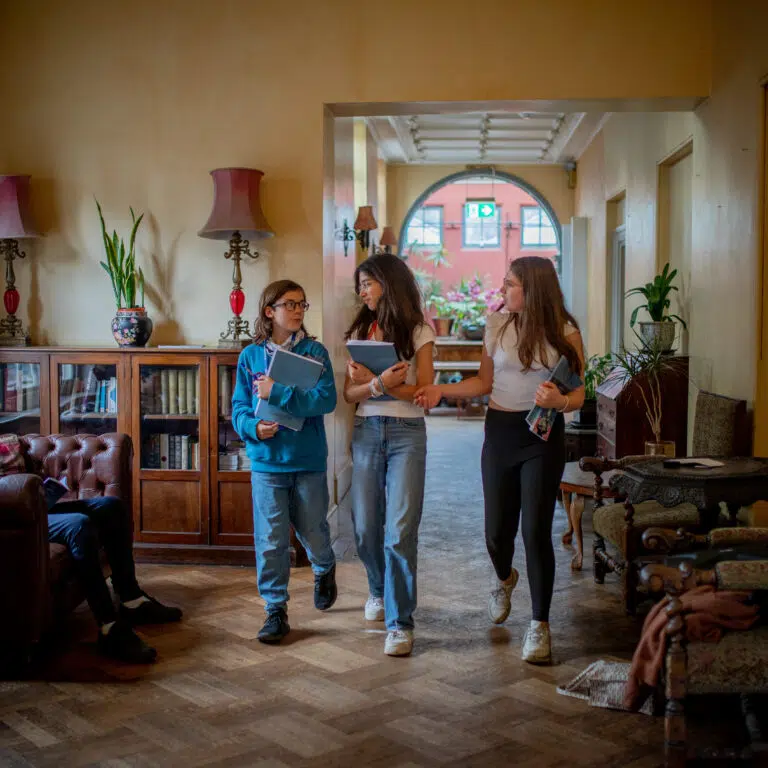 three teenagers walking along with school books
